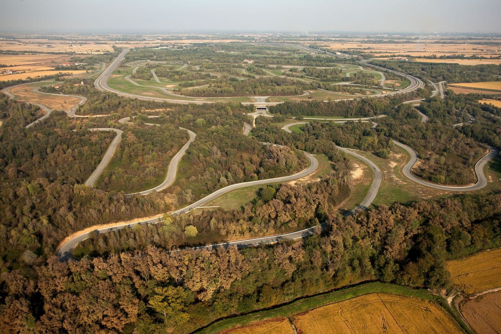 Veduta aerea di un intricato complesso di piste automobilistiche immerse nel verde della pianura.